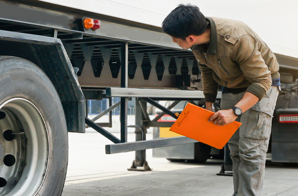 White semi-truck with man inspecting with a clipboard | Bauer Automotive Service