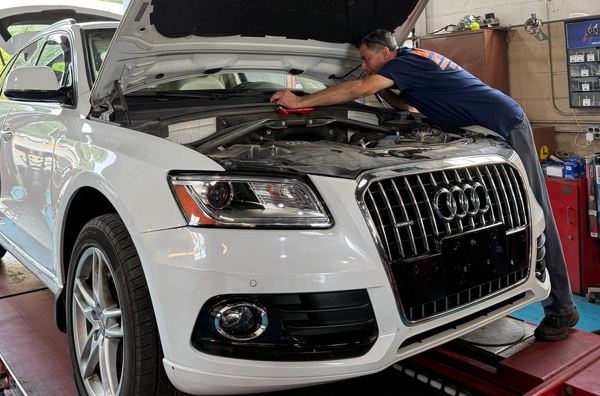 Technician performing repair on white car | Bauer Automotive Service