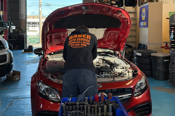 Our Expert Staff Performing Diagnostics on Red Car | Bauer Automotive Service